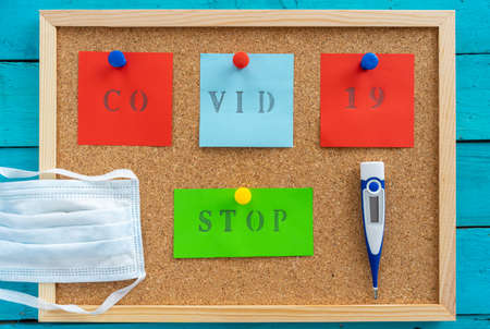 Cork board with caution message to fight covid-19 on a blue wooden table