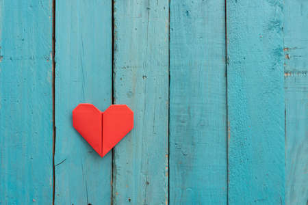 Origami hearts of different colors and sizes in composition on weathered blue wooden backgroundの写真素材