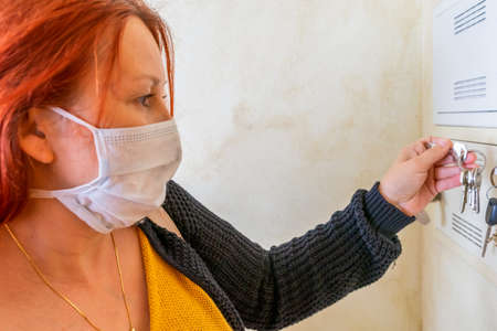 Precious redhead woman sweater and mask to prevent coronavirus preparing to leave the house holding keysの写真素材