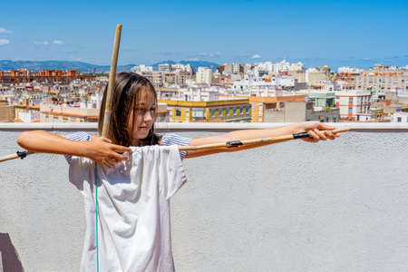 Pretty little girl dressed in a white and blue striped dress posing fun on the terrace of her house. Fun conceptの写真素材