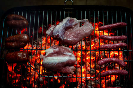 View of a half-done night barbecue with sausages, hamburgers, pork and bacon. Selective focusの写真素材