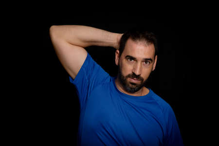 Bearded man dressed in blue t-shirt posing against black background. Fashion concept