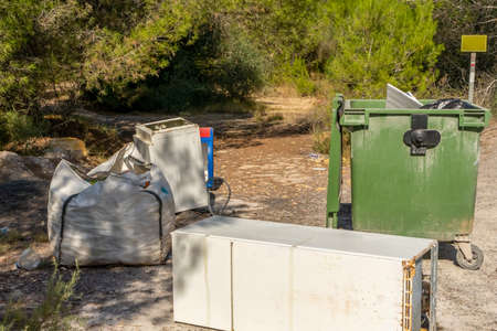 Garbage and household appliances dumped in the middle of a mountain with a pine forest. Dirt concept