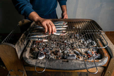 Man cooking a barbecue of fresh sardines on a charcoal barbecue. Healthy food concept