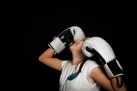 Beautiful little girl with boxing gloves posing funny on black background. Exercise conceptの写真素材