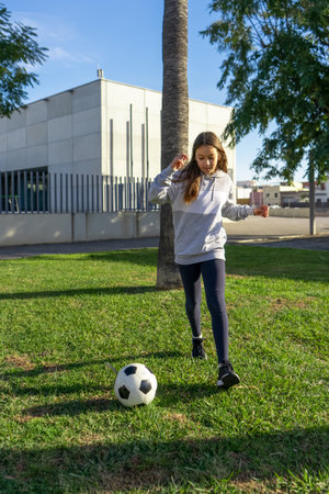 Beautiful little girl playing soccer in a nice park with natural grass on a sunny winter day. Exercise and healthy life conceptの写真素材
