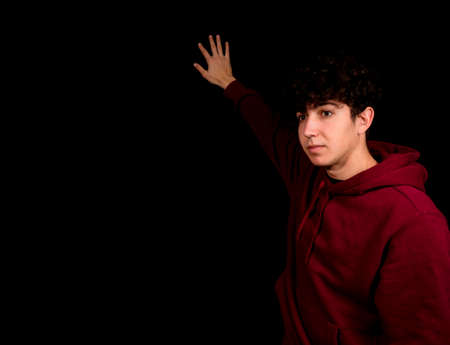 Attractive young man with curly hair posing on black background. Fashion concept