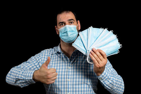 Handsome bearded man wearing a plaid shirt and surgical mask to protect himself from virus by...