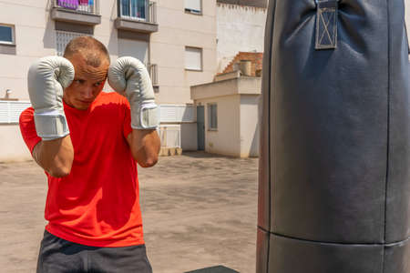 Joyful young man boxing in the street. Sports and health concept. Outdoor training. A young man is...