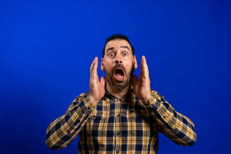 Angry young man yelling screaming. Hipster man with beard in blue plaid checkered shirt Isolated on...