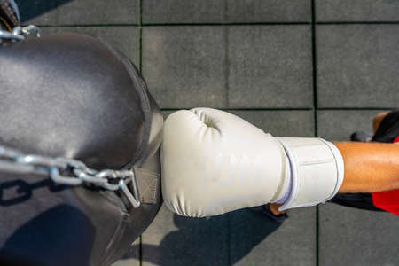 View from above of a fist with a white boxing glove hitting a punching bag. Training conceptの写真素材