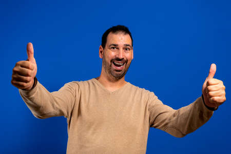 Young handsome man approving doing positive gesture with hand, thumbs up smiling and happy for...