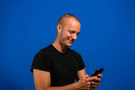 Portrait of interesting and handsome european man holding telephone while texting, isolated over...