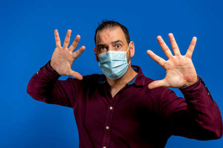 Front view of alarming man with hygienic protective mask stop, fear of coronavirus infection,...