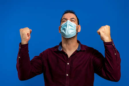 Bearded happy man 40s in purple shirt, sterile face mask safe from coronavirus covid-19 during...