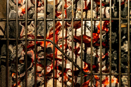 View of a rusty old grill on top of some smoldering charcoal embers ready for barbecue meat to be placed.の写真素材