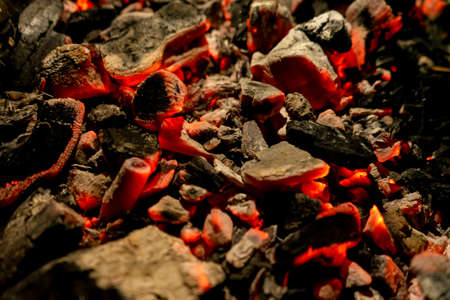 Background of burning and glowing embers. smoldering embers of fire. flicker of burning coals at night. Selective focus.の写真素材