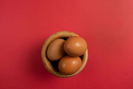 Eggs in the wooden bowl and red background for healthy, organic food. Copy space for your textの写真素材