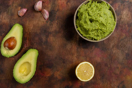 Traditional latinamerican mexican sauce guacamole in clay bowl, cut half avocado and avocado...
