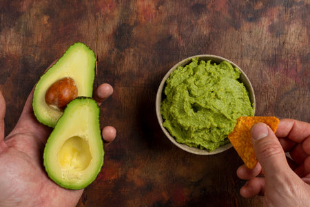Traditional latinamerican mexican sauce guacamole in clay bowl, cut half avocado and avocado...
