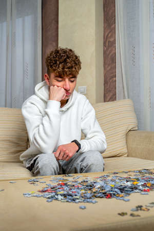 Young man sitting on a sofa doing puzzles in an isolated place.