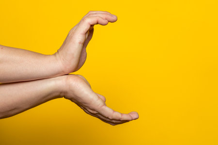 Strong male hands making the gesture of a kame hame, ready to launch a vital wave of energy. Isolated on yellow background.の写真素材