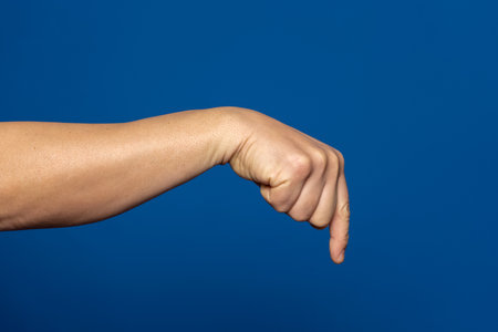 Strong hand of man pointing index finger down isolated on blue background.の写真素材