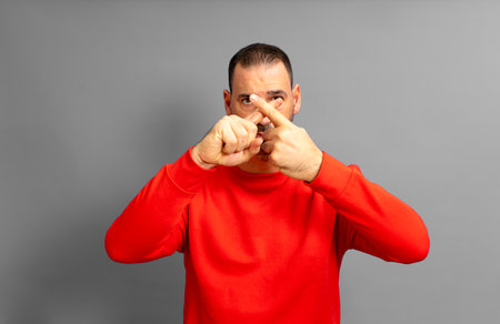 Hispanic man with a beard in his 40s making a stop gesture crossing his index fingers, isolated over gray backgroundの写真素材