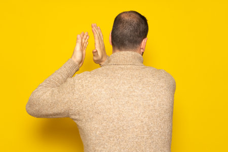 Man with alopecia problem energetically patting his back, excited by the spectacle he has just witnessed. Isolated on yellow background.の写真素材
