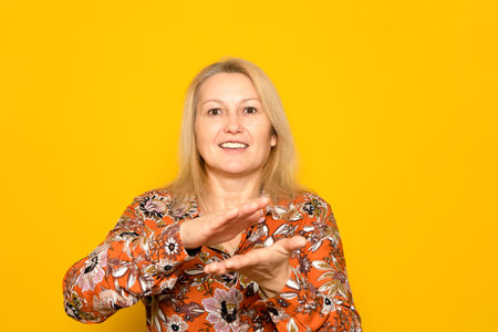 Caucasian blonde woman in her 40s clapping her hands visibly excited by the great spectacle she witnessed, isolated on yellow studio background.の写真素材