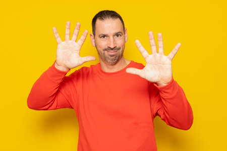 Front view of a Caucasian man with short hair wearing a red jumper with palms facing him, camera facing palm, touching an interactive virtual screenの写真素材