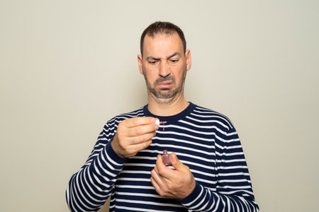 Bearded hispanic man about 40 years old wearing a striped sweater with a disgusted and bewildered...