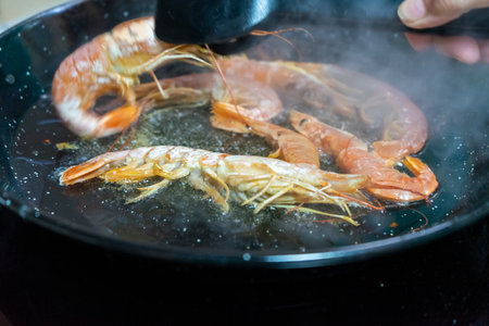 Horizontal image of a woman cooking some large shrimps in the pan in her kitchen. Gourmet food conceptの写真素材