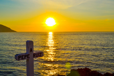 A cross dedicated to the death of sailor Pepe Ruiz in Punta Robaleira, Cabo Home, Spain. Beautiful sunset over the sea and rocksの写真素材