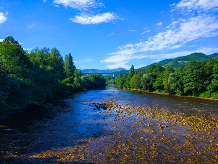 Big river crossing a forest with a lot of green trees. Few water and rocks.の写真素材