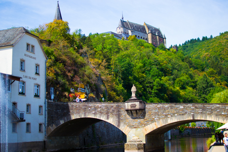 Vianden Castle on a hill with a bridge, a restaurant and Our river in Vianden, Luxembourgのeditorial素材