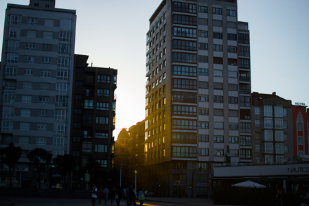 Orange sunrays through two buildings in a sunset in Gijon, Asturias, Spainのeditorial素材