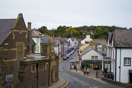 Conwy, Wales; 10/14/2018: Street in Conwy with typical houses and a green hill with trees at the backgroundの写真素材