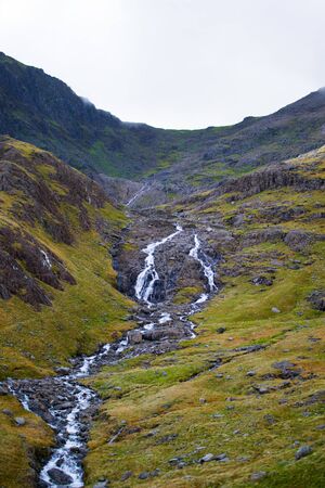 Vertical picture of a small brook through the green hillside of a mountain in Snowdonia, Walesの写真素材