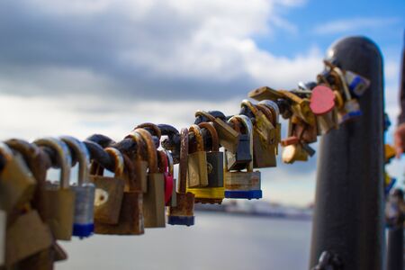 Extreme close up of multicolored padlocks (or locks) in the fence of a bridge in Liverpool dock,...