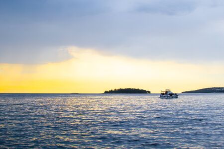 View of the horizon over the Adriatic Sea, with a boat sailing, during the sunset of a cloudy day while rainingの写真素材
