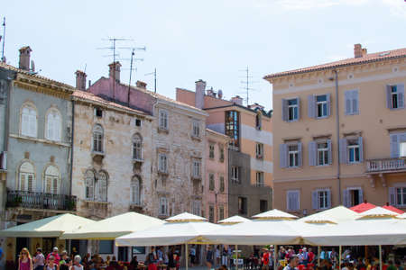 Facades of the colorful buildings of Forum Square, the main square in the old town of Pula, Croatia, with parasols of the terraces of the barsのeditorial素材