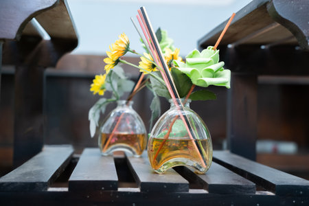 Room freshener with yellow and green flowers and incense inside a vase on the table