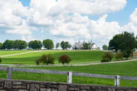 Countryside landscape with farm house and fence on green meadow.