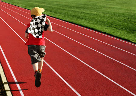 Boy with a checkered flag running on a racetrackの写真素材