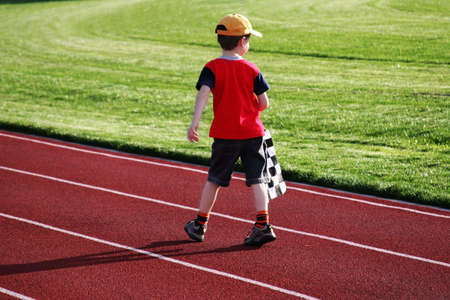 Boy with a checked flag walking on a racetrackの写真素材