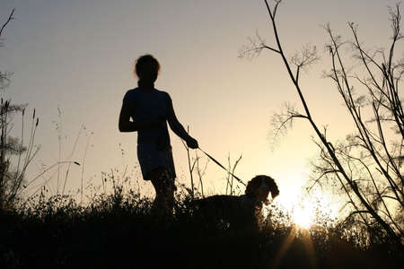 Girl and her dog at sunsetの写真素材