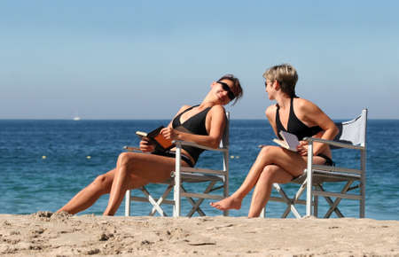 2 women reading on the beachの写真素材
