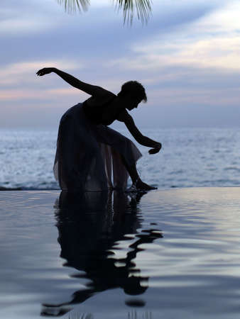 Woman and her reflection in a pool by the oceanの写真素材