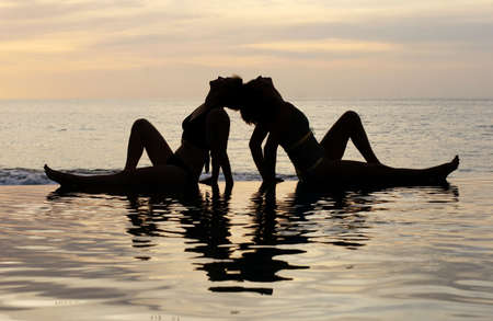 Women and their reflections in a pool by the oceanの写真素材
